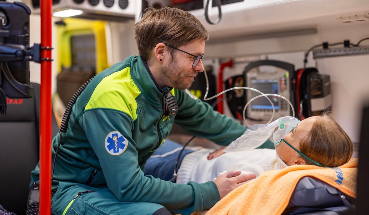 Ambulansmedarbetare vårdar patient i ambulans.