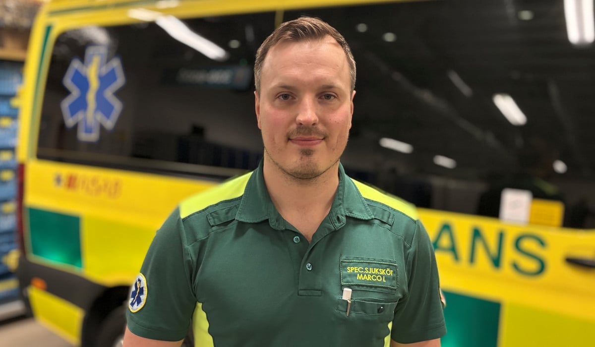 En man står framför en gul och grön ambulansbuss.