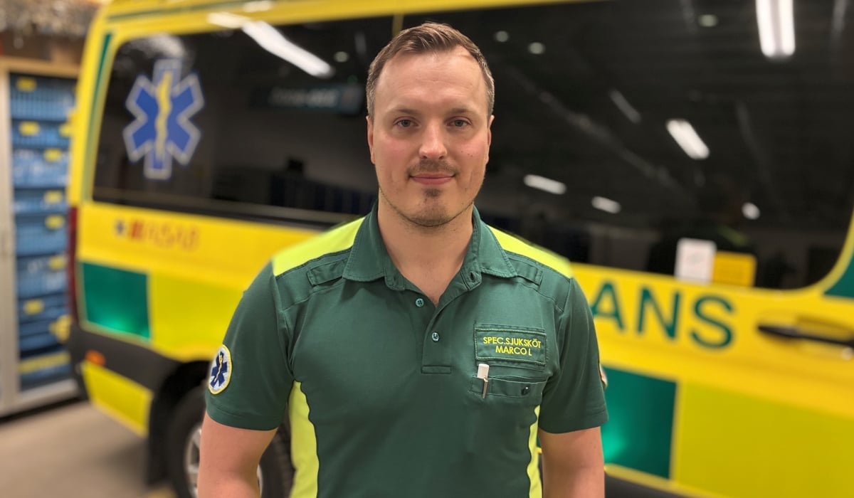 En man står framför en gul och grön ambulansbuss.