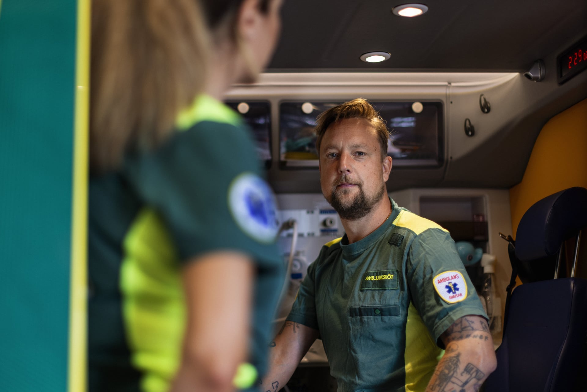 Man och kvinna i uniform arbetar inne i en ambulans.