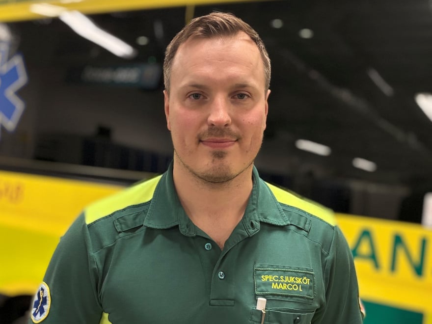 En man står framför en gul och grön ambulansbuss.