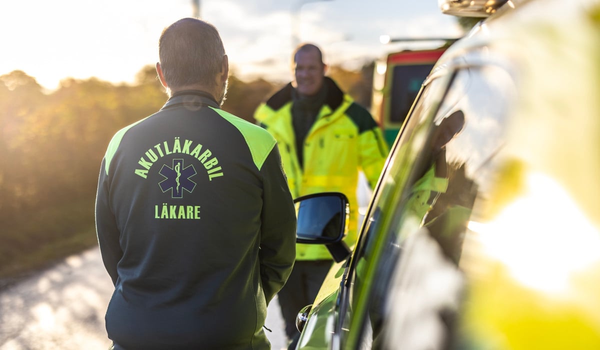 Läkare och sjuksköterska som står och pratar vid en ambulans