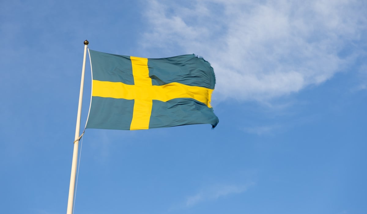 Svenska flaggan som vajar på en stång.