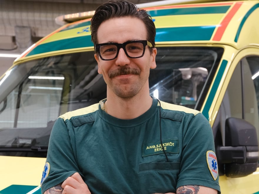 En man i ambulanskläder som står framför en ambulans.