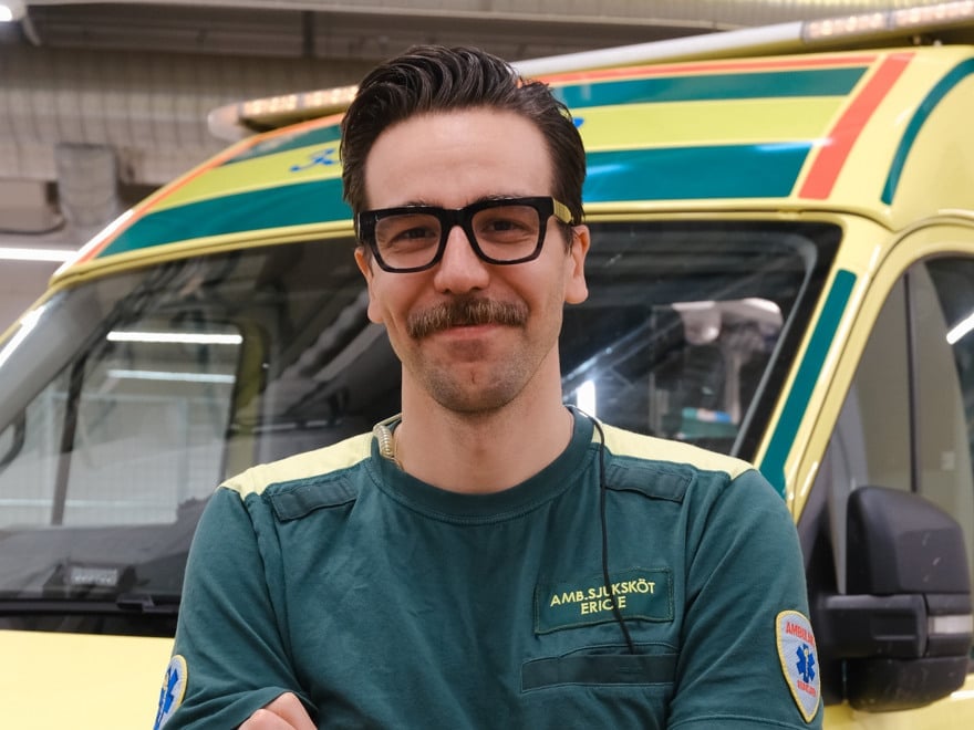 En man i ambulanskläder som står framför en ambulans.