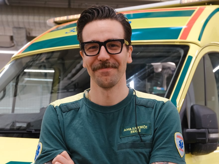 En man i ambulanskläder som står framför en ambulans.