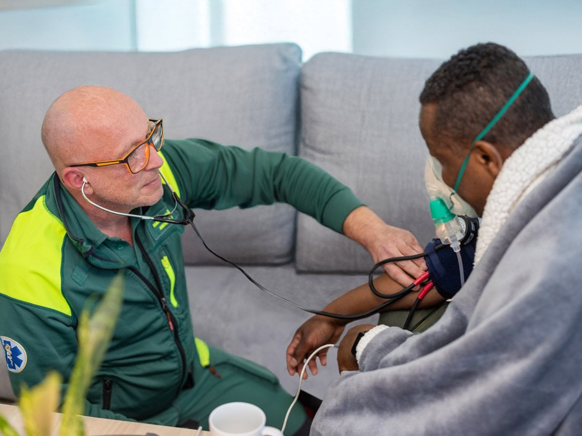 En man med stetoskop som lyssnar på en patient.