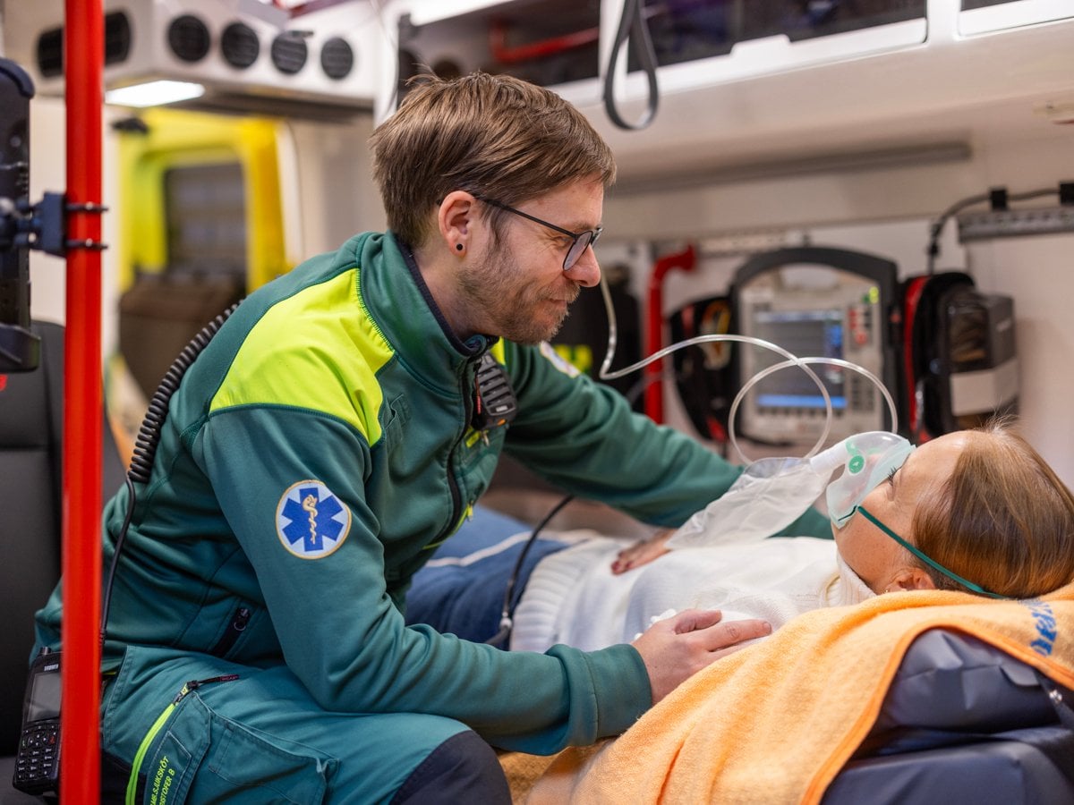 Ambulansmedarbetare vårdar patient i ambulans.