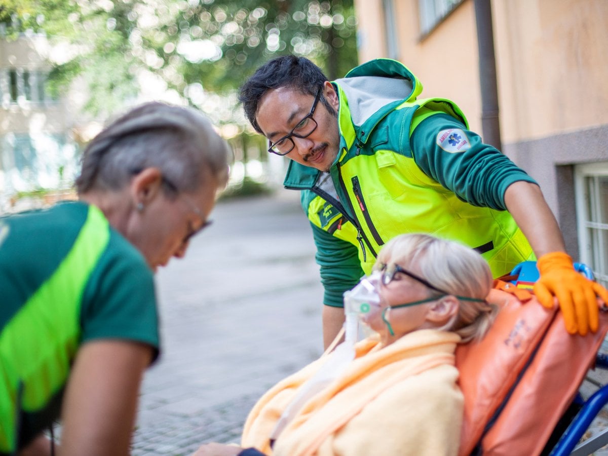 Två ambulansmedarbetare pratar med en patient
